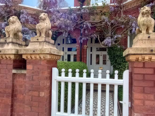 Figure 176: Typical example of the entrance to a Lion House, with Lion statues on the gate piers, white-painted timber gate, tessellated tile path, and original door